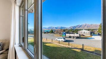 A window view of a parking lot with a mountain backdrop, a truck, and a car.
