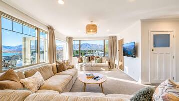 A spacious living room with a large sofa, a coffee table, and a television on the wall.