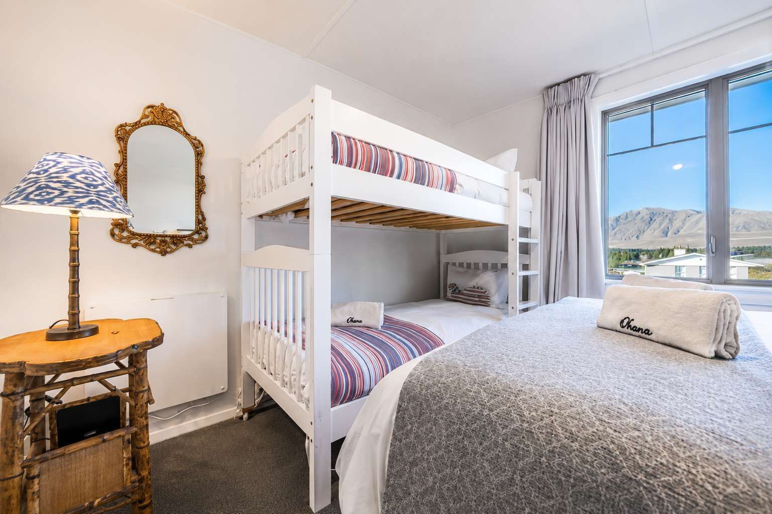 A bunk bed room with a lamp, a mirror, and a view of the mountains.