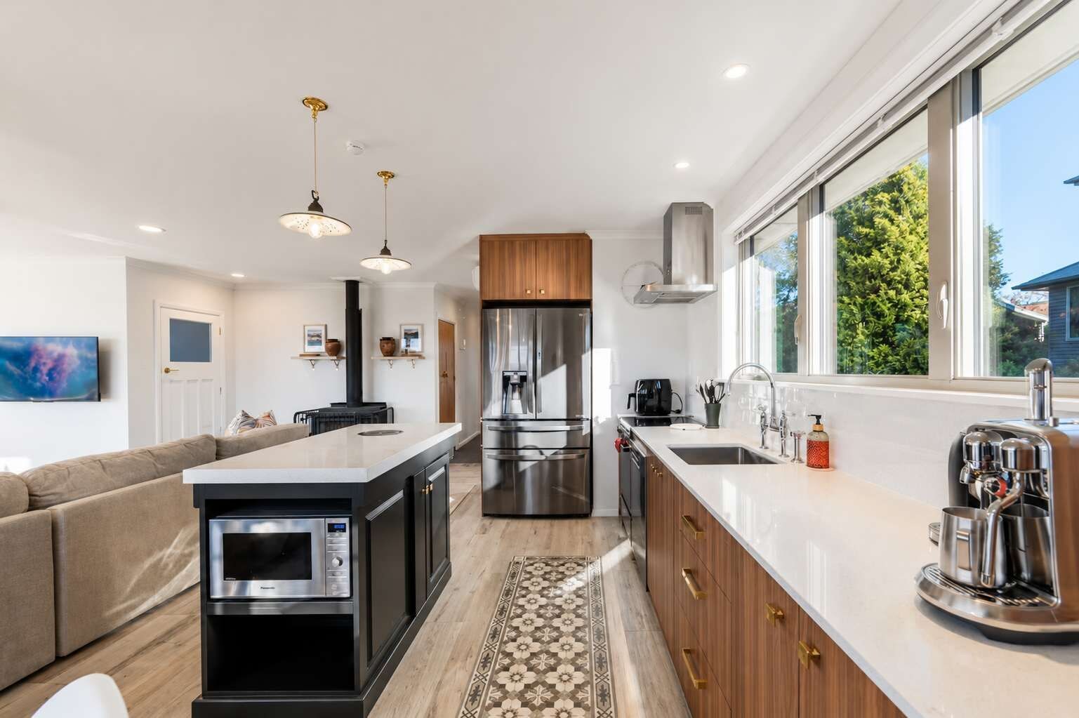 A modern kitchen with a central island, stainless steel appliances, and a large window providing natural light.