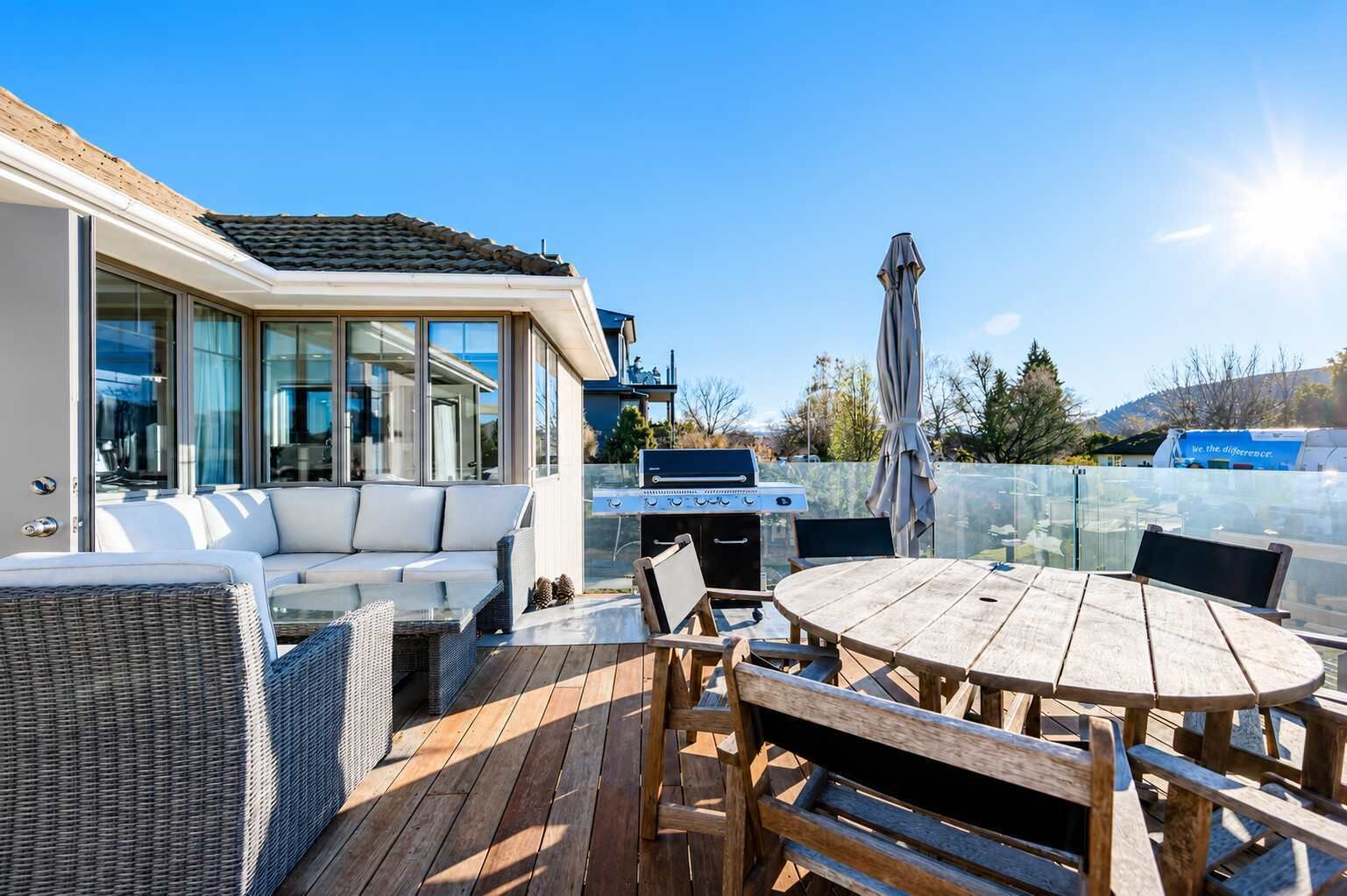 An outdoor patio with a dining table, chairs, a grill, and a sofa.