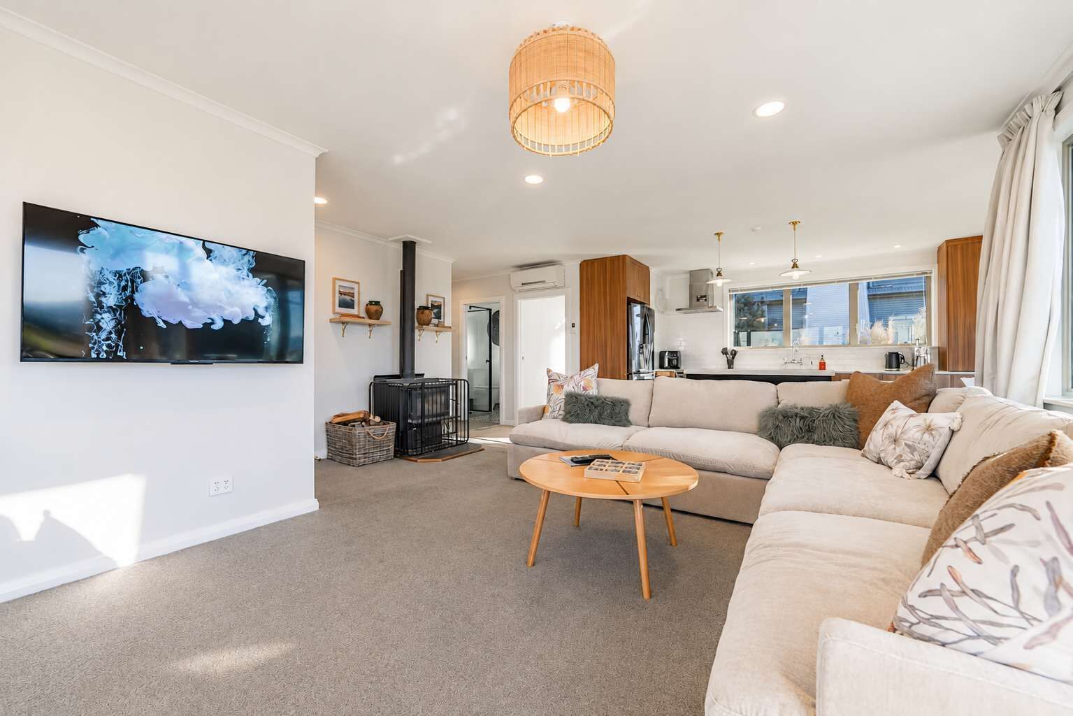 A modern living room with a large flat-screen TV, a sofa, a coffee table, and a fireplace.