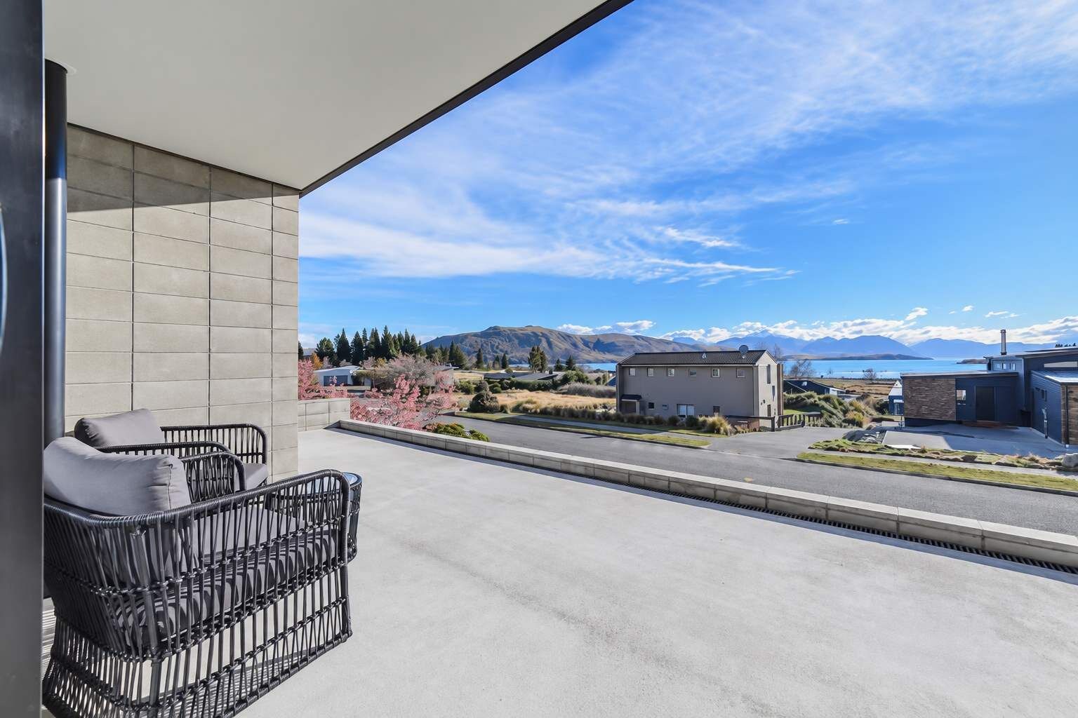 Un balcon offrant une vue sur un quartier résidentiel, une chaîne de montagnes et une étendue d’eau.