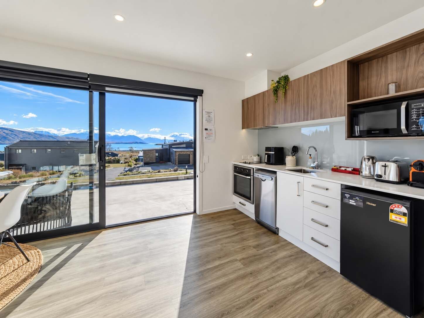A modern kitchen with a view of mountains, a dining area with a glass door, and a black refrigerator.