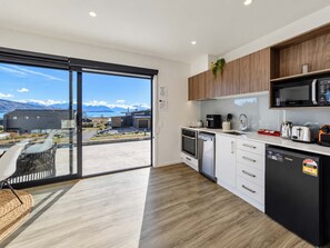 A modern kitchen with a view of mountains, a dining area with a glass door, and a black refrigerator.