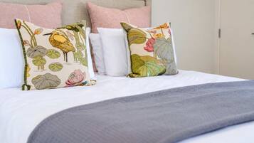 A bed with a grey blanket, two decorative pillows with floral patterns, and a headboard.