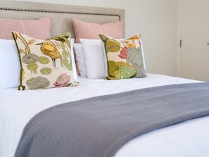A bed with a grey blanket, two decorative pillows with floral patterns, and a headboard. - The Nook | Lake Views + Private Patio | Tekapo (Lake Tekapo)