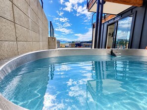 A clear swimming pool with a view of mountains and a modern building in the background. - The Nook | Lake Views + Private Patio | Tekapo (Lake Tekapo)