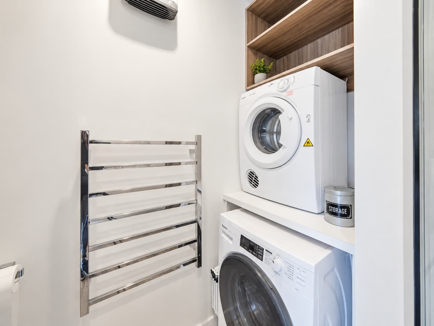 A laundry room with a front-loading washing machine, a dryer, and a metal drying rack.