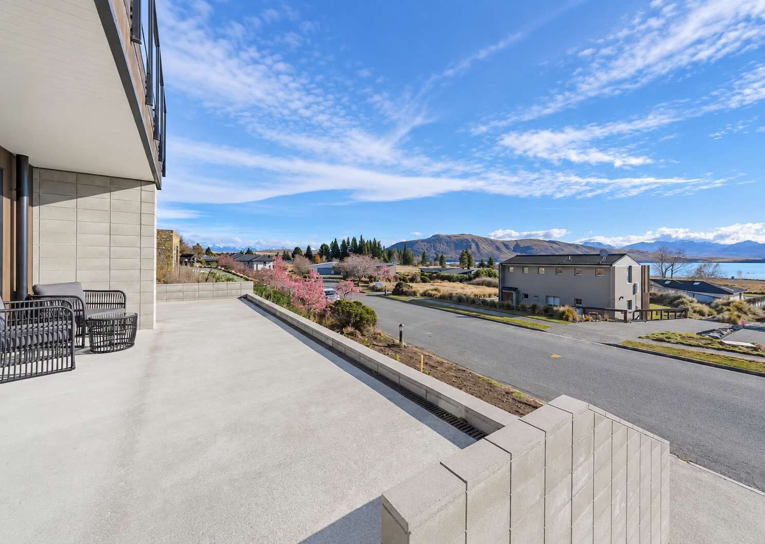A residential property with a balcony, a view of a lake, and mountains in the background.