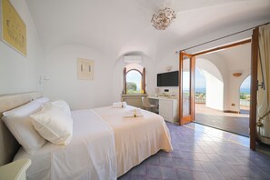 Ein Hotelzimmer mit Bett, Schreibtisch, Fernseher und Blick ins Freie.