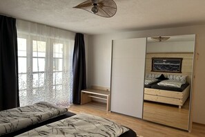 Ein Schlafzimmer mit Bett, Schreibtisch, Stuhl und einem großen Spiegel.