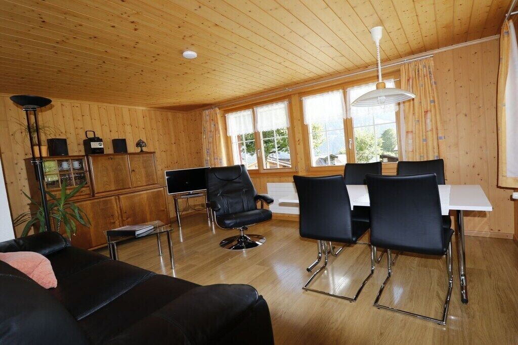 Une pièce aux murs lambrissés, avec une table à manger, des chaises noires, un canapé et une lampe.