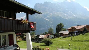Un chalet doté d’un balcon, décoré aux couleurs du drapeau suisse, et offrant une vue sur la montagne.