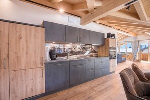 Eine moderne Küche mit Holzbalken, grauen Schränken und Wandgemälde mit Bergblick.