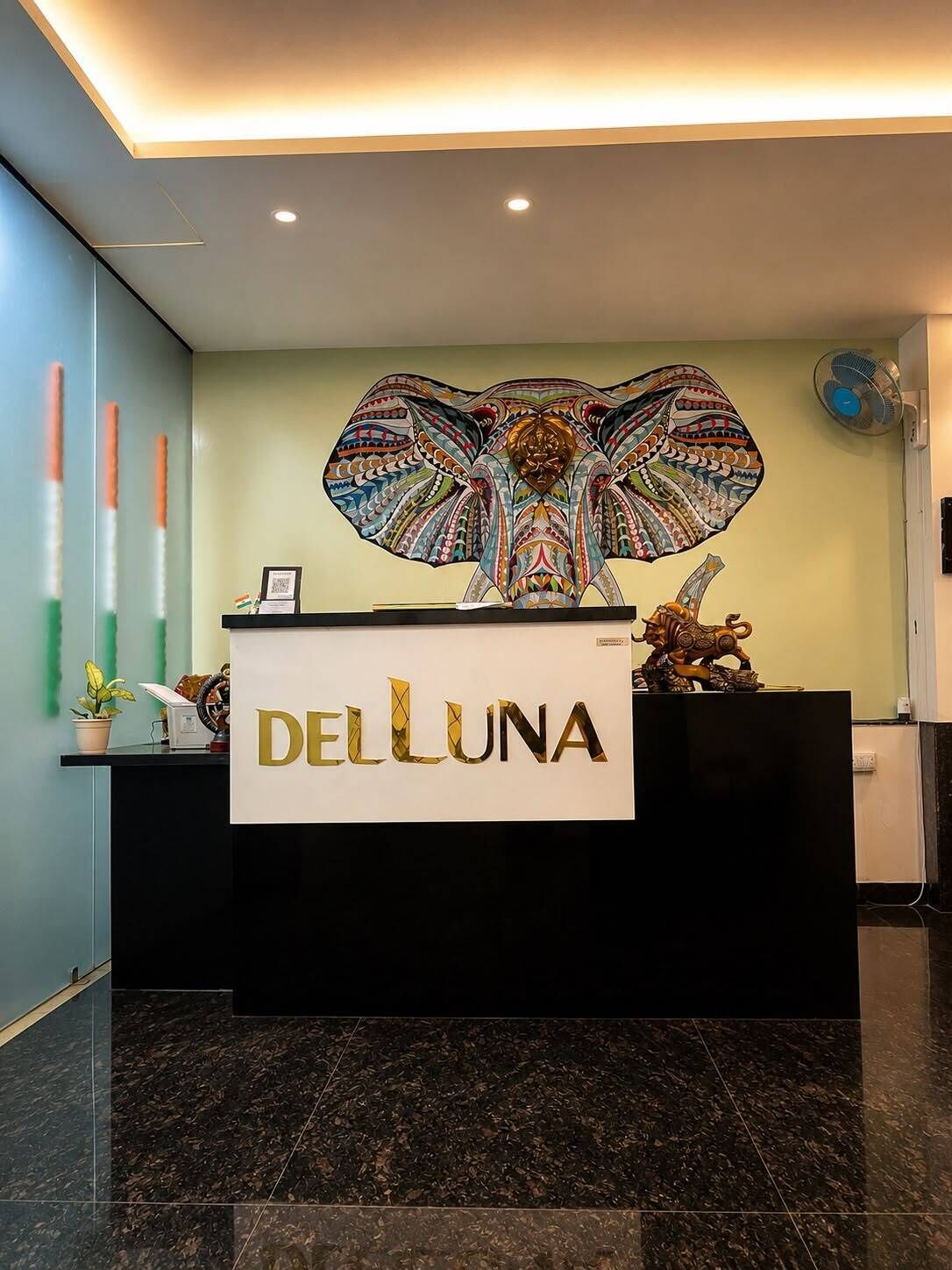 A reception desk with a large, colorful artwork above it and the name 'DELLUNA' prominently displayed.