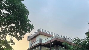 Un edificio moderno de dos pisos con techo plano, ventanas amplias y un balcón.