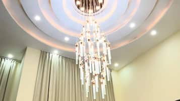 A room with a chandelier, curtains, and a staircase.