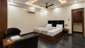 Quarto de hotel moderno com cama, cadeira, mesa de cabeceira, ar condicionado e ventoinha de teto.