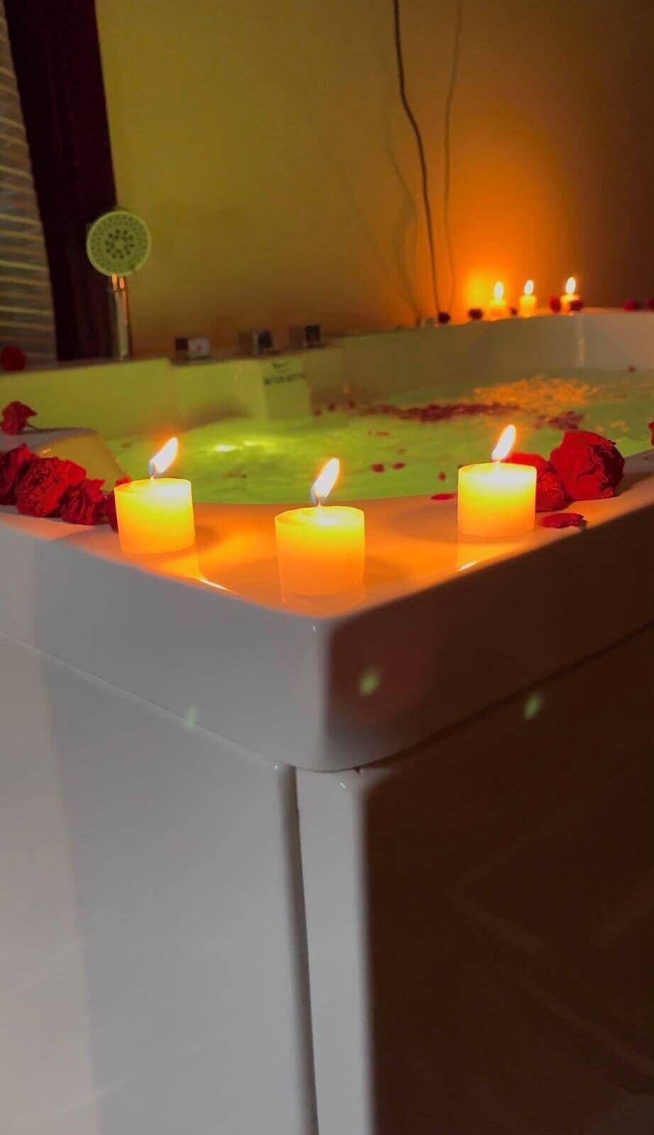 Una vasca da bagno con candele e petali di rosa.