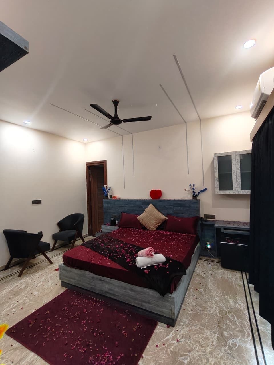 Ein Schlafzimmer mit einem Bett, einem Deckenventilator, einem Fernseher und einer Tür.