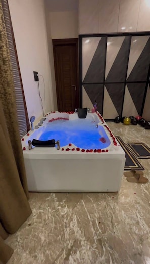 Un área de spa con un jacuzzi, una puerta de madera y piso de baldosas.
