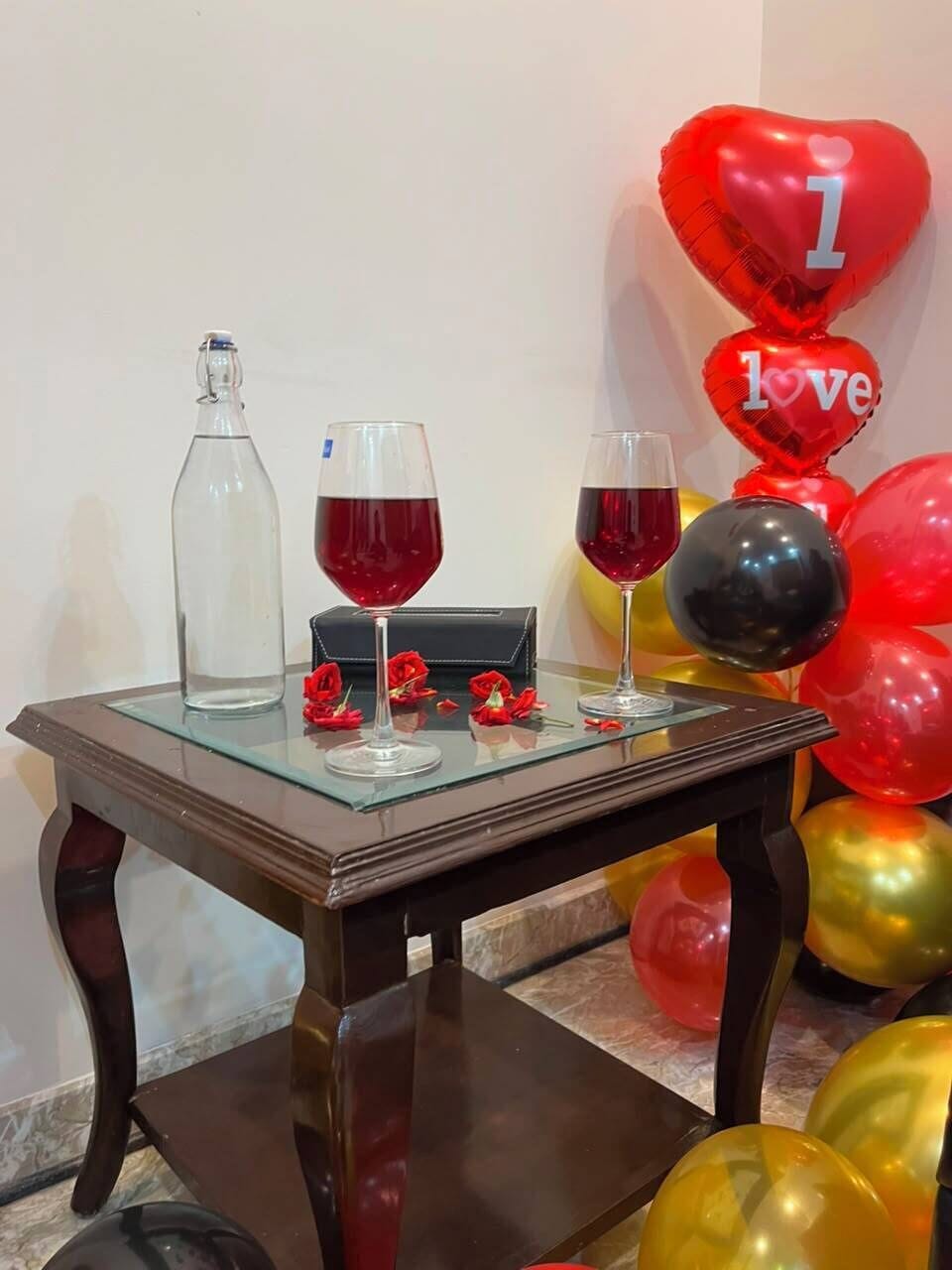 Une table avec deux verres de vin rouge, une bouteille et un sac noir.