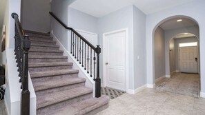 Un escalier avec une rampe, des marches recouvertes de moquette et une porte en haut.