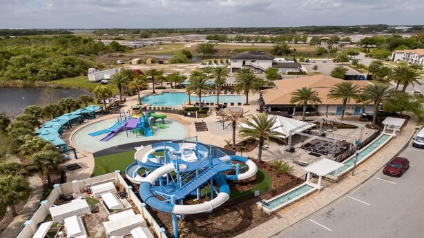 Een waterpark met meerdere glijbanen en zwembaden, omringd door palmbomen en een parkeerplaats.