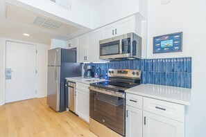 Eine moderne Küche mit Edelstahlgeräten, weißen Schränken und einer blauen Spritzschutzwand.