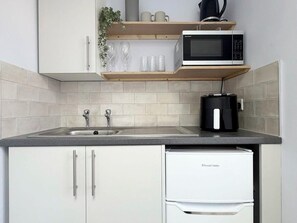 Eine Küche mit Spüle, Mikrowelle, Kaffeemaschine und Kühlschrank.