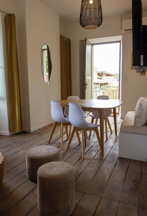 A modern living room with a round wooden table, white chairs, a sofa, and a large mirror. - Lisael, Vacation Rental for 4 to 6 People Near Puy du Fou (Mauléon)