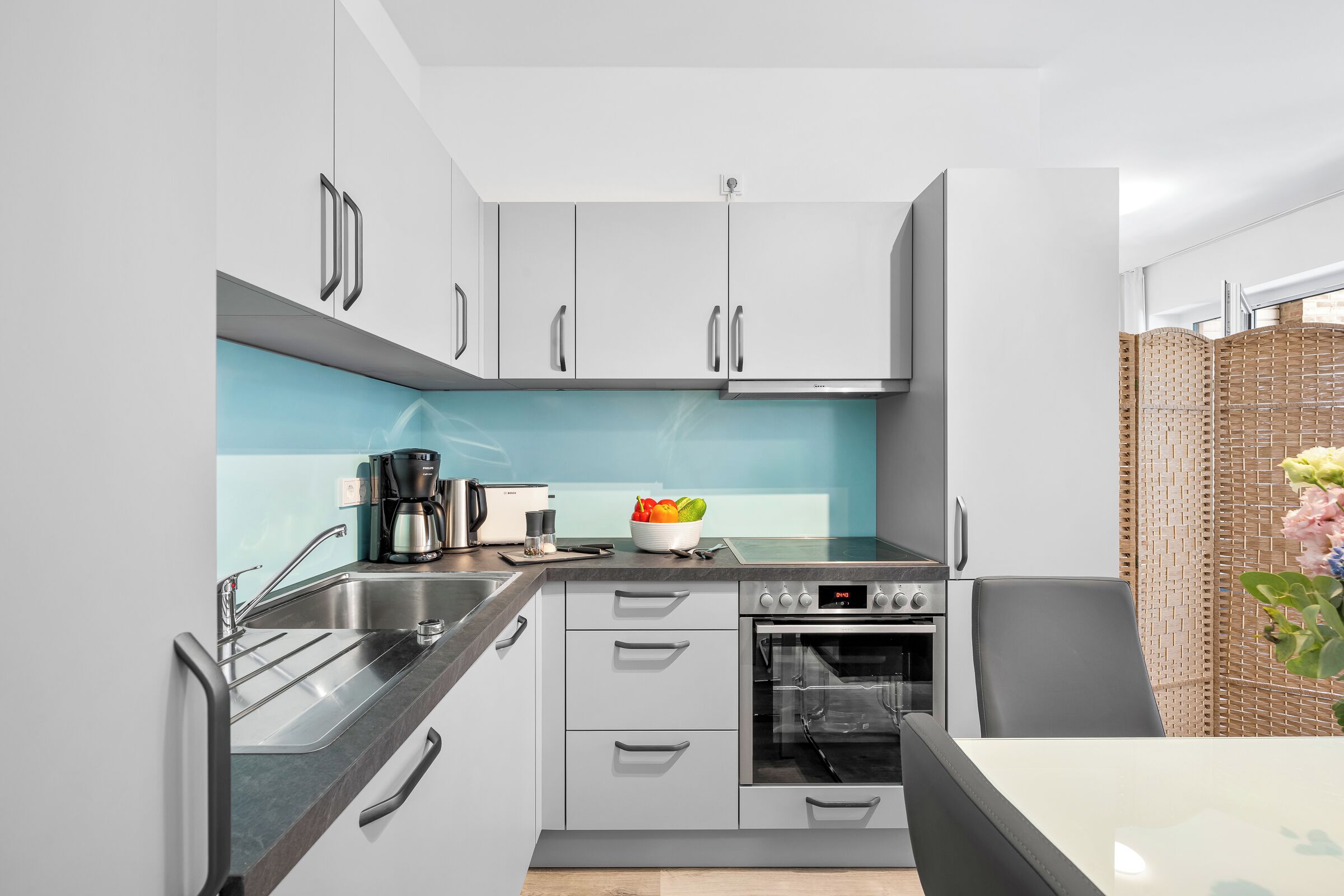 Una cucina moderna con mobili grigi, forno integrato e macchina per il caffè.