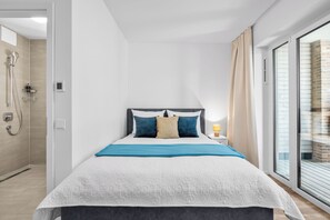 Ein modernes Schlafzimmer mit Bett, Dusche und Blick auf ein Backsteingebäude.