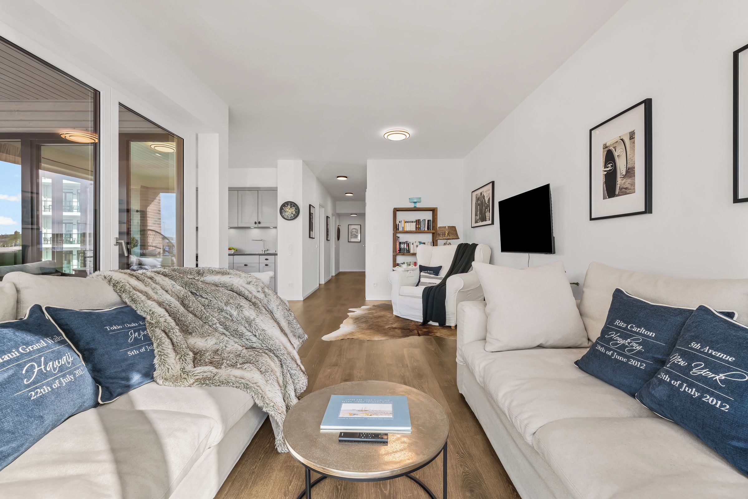 A modern living room with a sofa set, a coffee table, and a view of the kitchen and dining area.