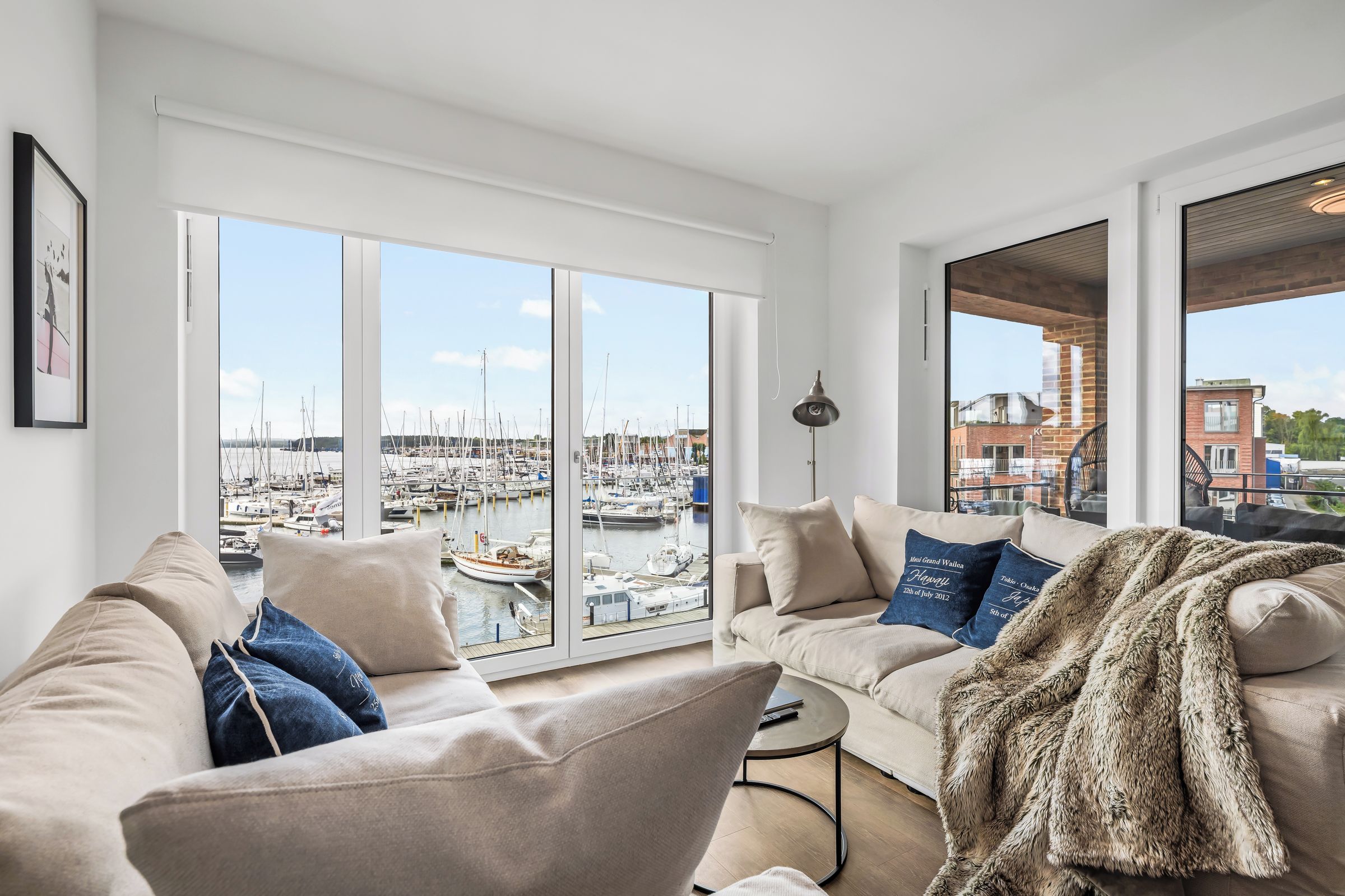 A spacious living room with a large bay window overlooking a marina.