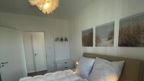 Ein Schlafzimmer mit einem großen Bett, Nachttischen, einem Kleiderschrank und Wandbildern.