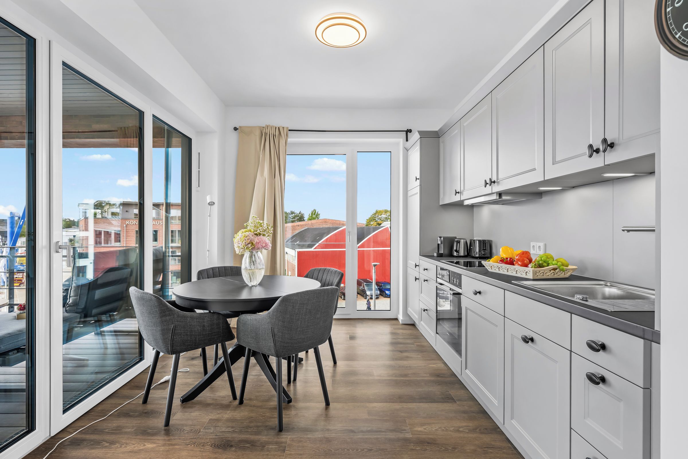 A modern kitchen with a dining area, large windows, and a view of the city.
