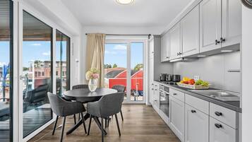 A modern kitchen with a dining area, large windows, and a view of the city.