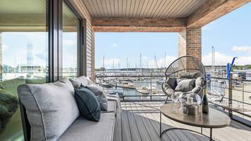 A modern balcony with a sofa and a table, overlooking a marina with boats.