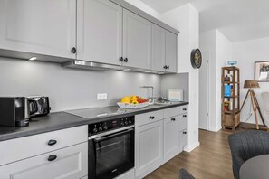 A modern kitchen with white cabinets, a black oven, and a stainless steel countertop. - Modern Apartment Pure Travemünde with Terrace, Parking and Partial Sea View (Lübeck)