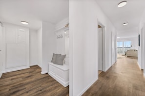 Een modern interieur met een houten vloer, witte muren en een bank met een gestreept kussen.