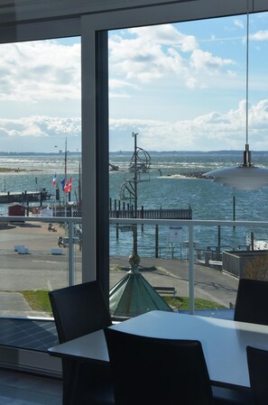 A view from a window overlooking a harbor with boats, flags, and a pier. - Spacious Apartment with exceptional Sea View and Wellness Area! (Wendtorf)