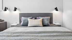 Ein ordentlich eingerichtetes Schlafzimmer mit Bett, Kissen, Nachttischen und Wandlampen.