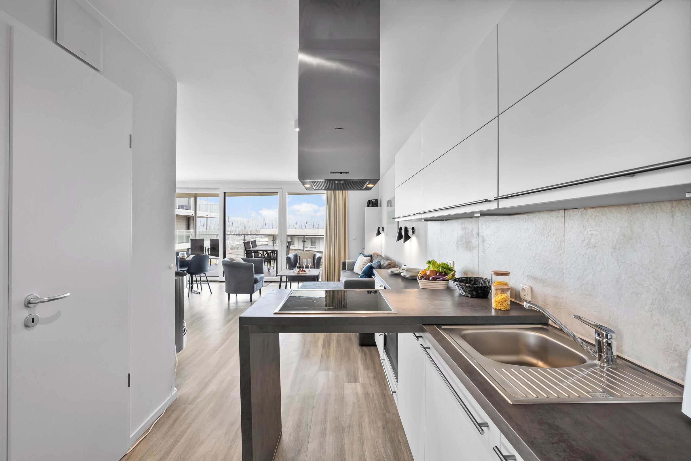 A modern kitchen with a central island, stainless steel appliances, and a view to a dining area.