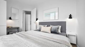 A modern bedroom with a large bed, bedside tables, a mirror, and a framed quote on the wall.