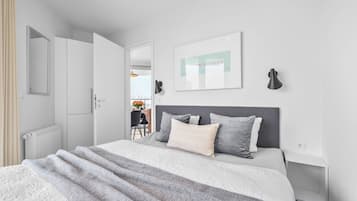 Ein modernes Schlafzimmer mit Bett, Nachttischen, Heizkörper, Spiegel und einem gerahmten Bild an der Wand.