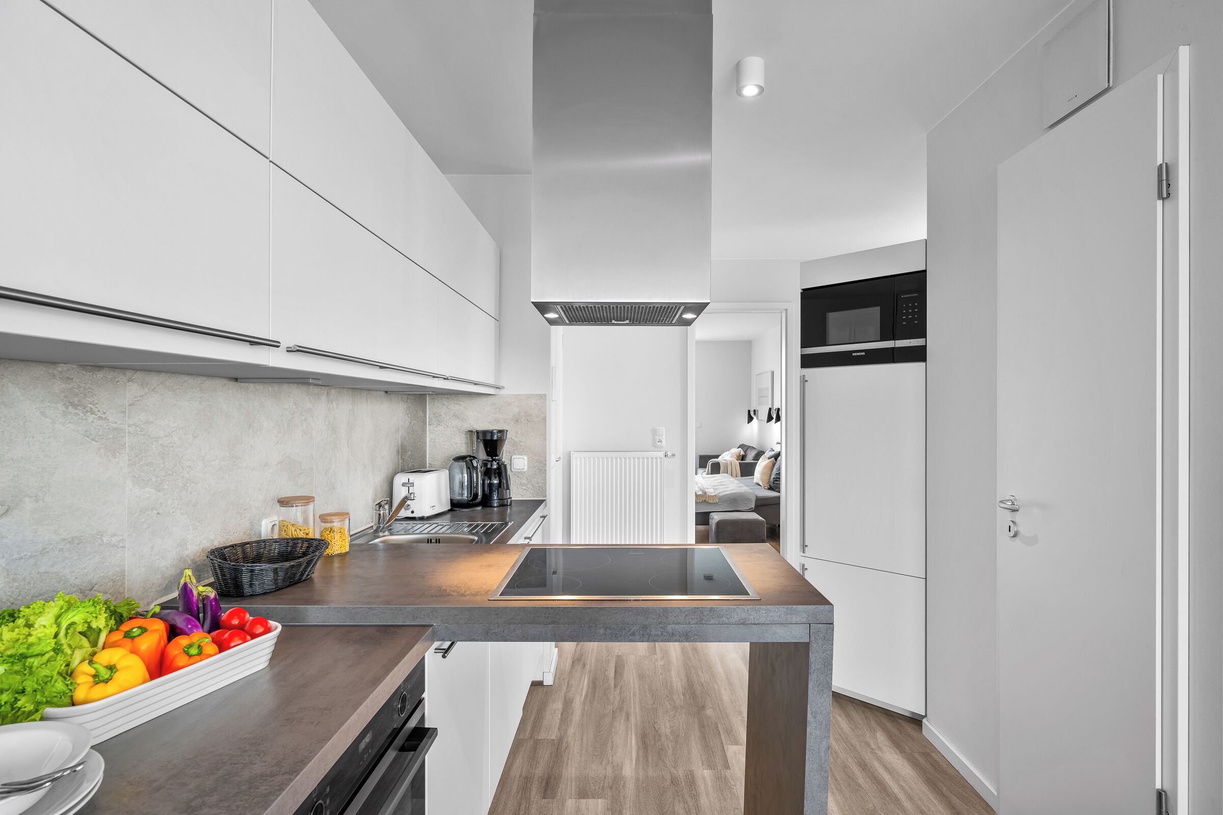 A modern kitchen with white cabinets, a central island, and a microwave.