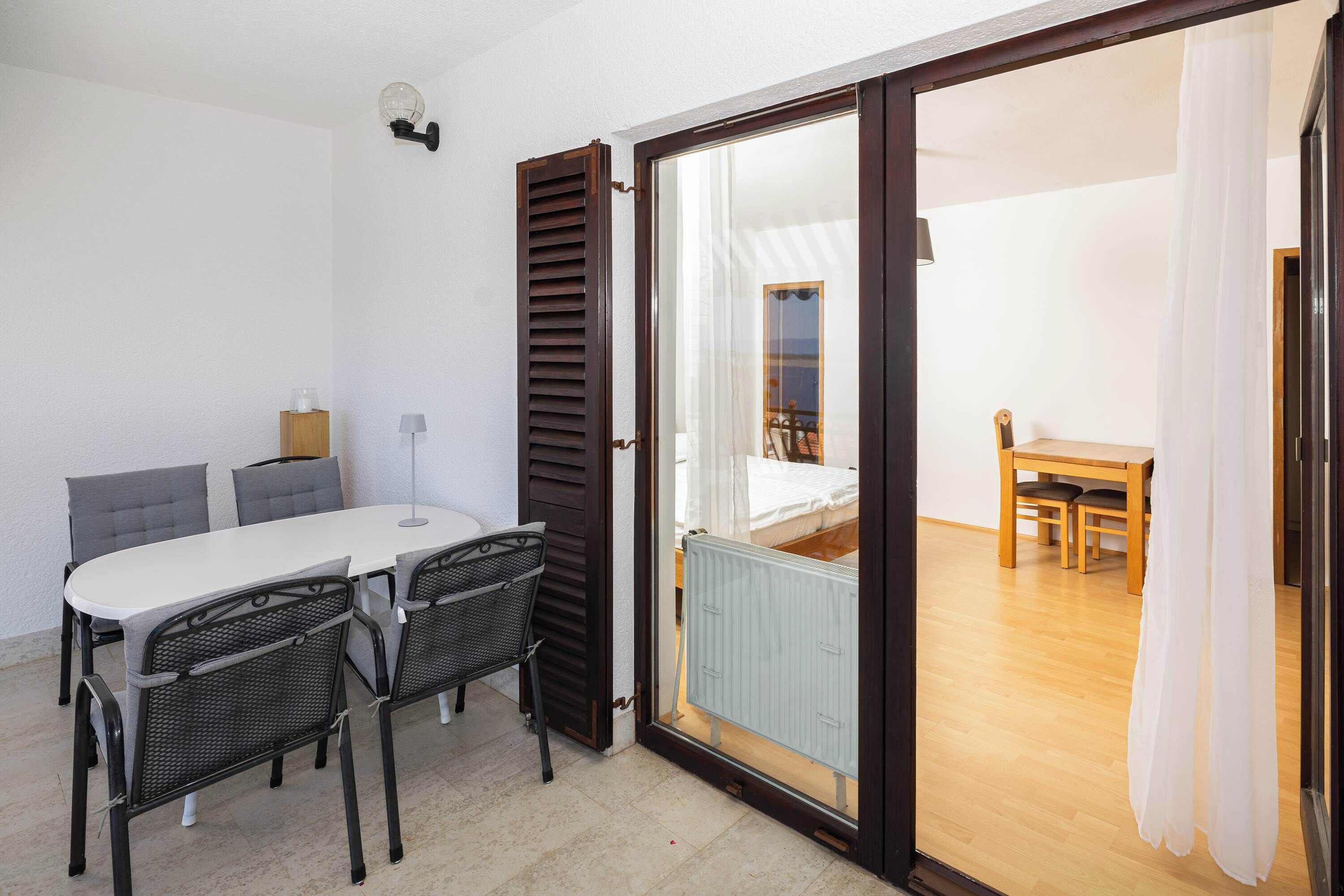 Une pièce comprenant une table à manger, des chaises, un radiateur et une porte-fenêtre coulissante donnant sur un balcon.