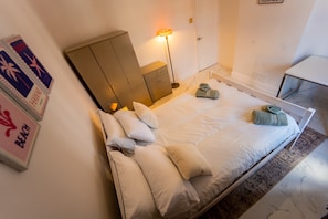 A bedroom with a bed, pillows, a nightstand, a lamp, and a wardrobe. - Stylish 2 Bedroom With Free Parking (Manchester)